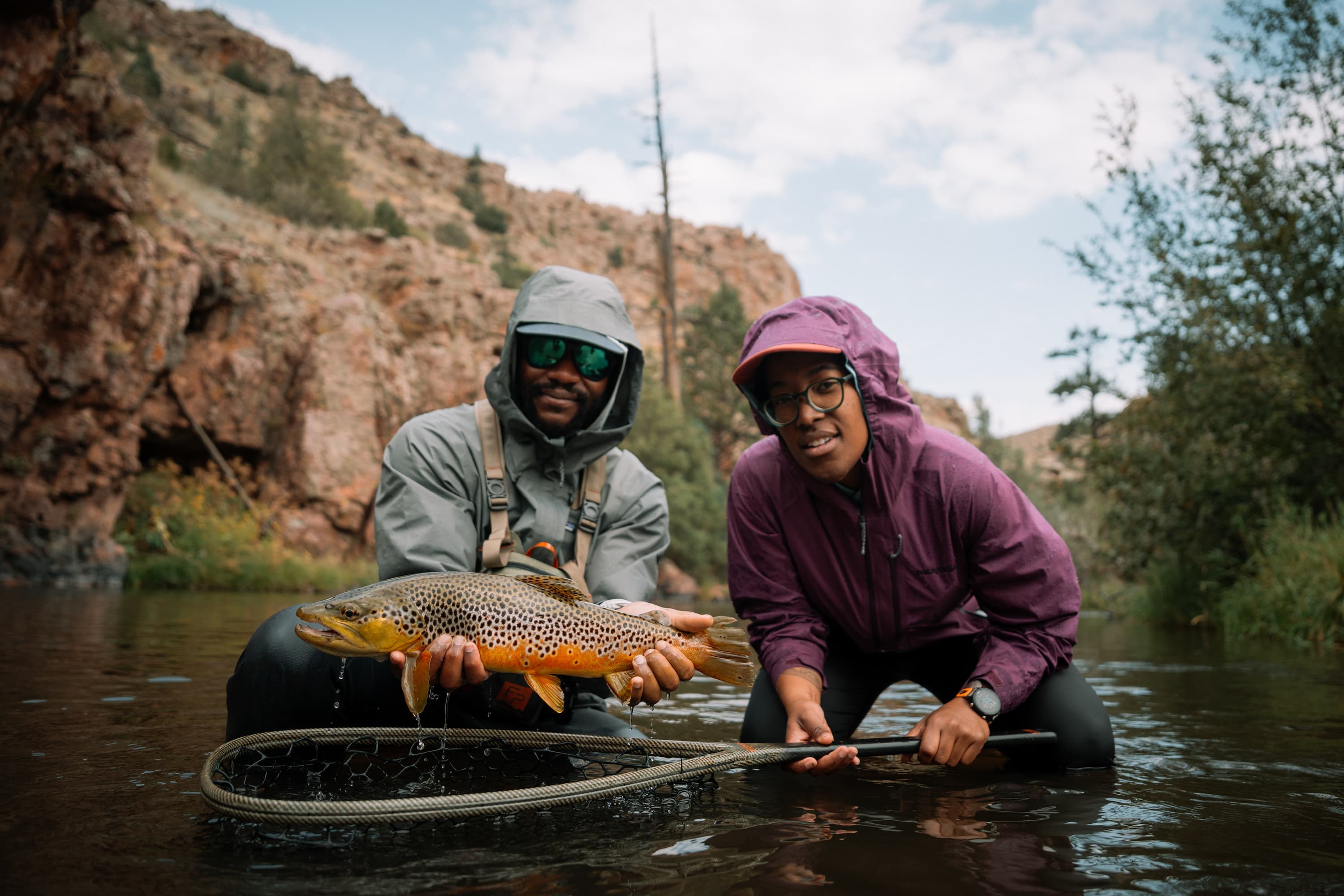 Two fishermen on the river, proudly holding a trout